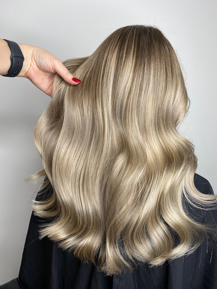 Salon client with long, thick blonde hair styled in loose waves