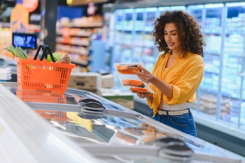 Woman looking at fresh salmon in a supermarket while shopping for omega-3-rich foods