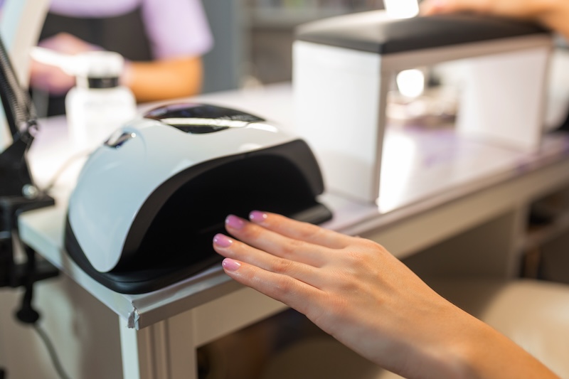 Client curing gel nails under an LED lamp as new UK rules ban TPO in newly supplied cosmetic products