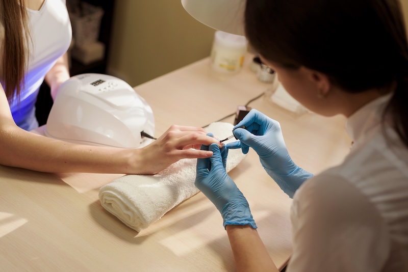 Nail technician applying gel polish during a professional salon manicure