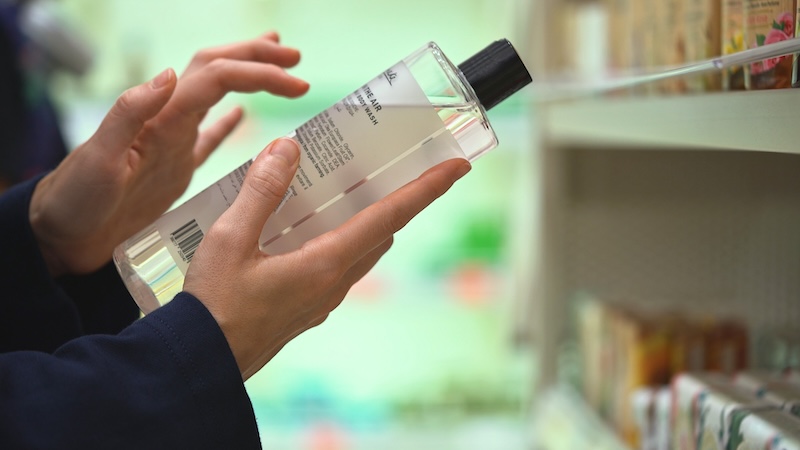 Woman reading the ingredient label on a cosmetic product to check its formulation