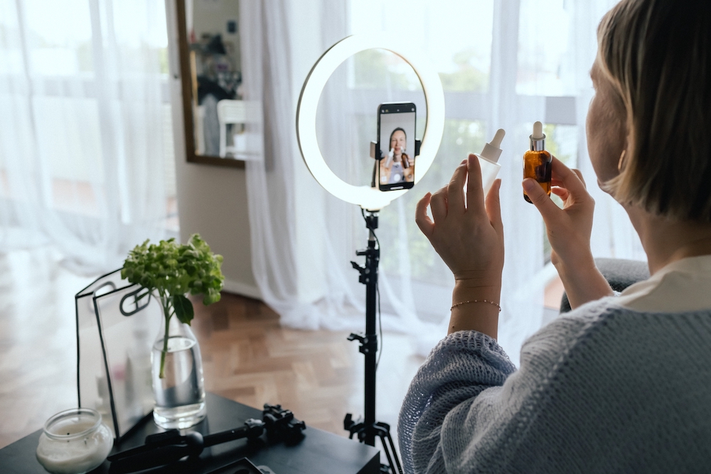 Woman filming skincare advice on her phone with a tripod and ringlight