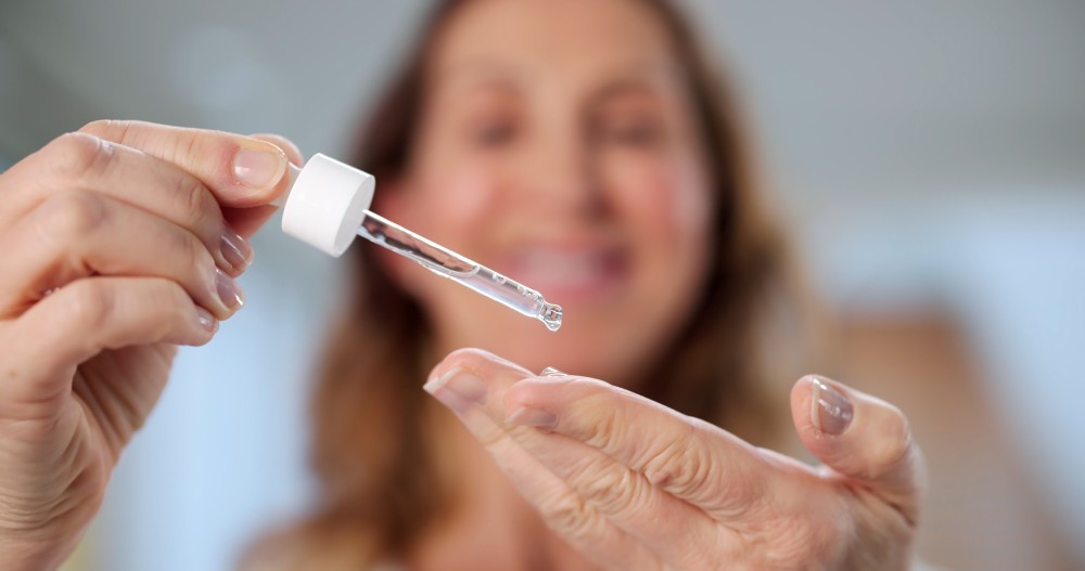 woman applying skincare pipette to her hand