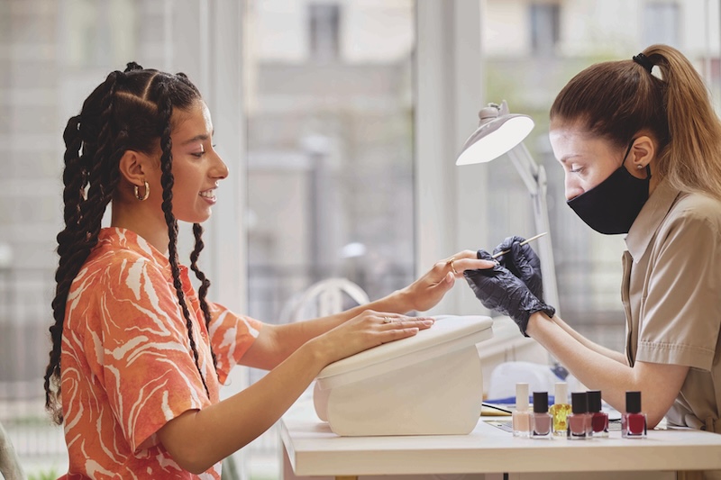Nail technician performing a manicure on a client in a beauty salon