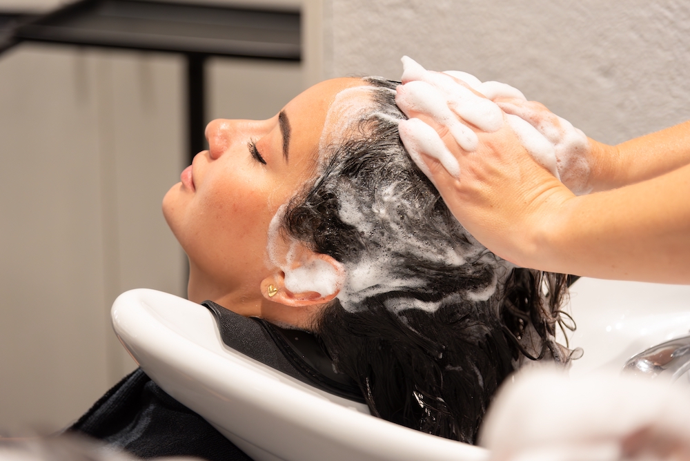 Woman relaxing at salon backwash having hair washed
