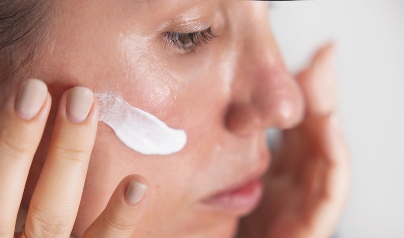 Woman applying skincare to her face to support redness-prone skin
