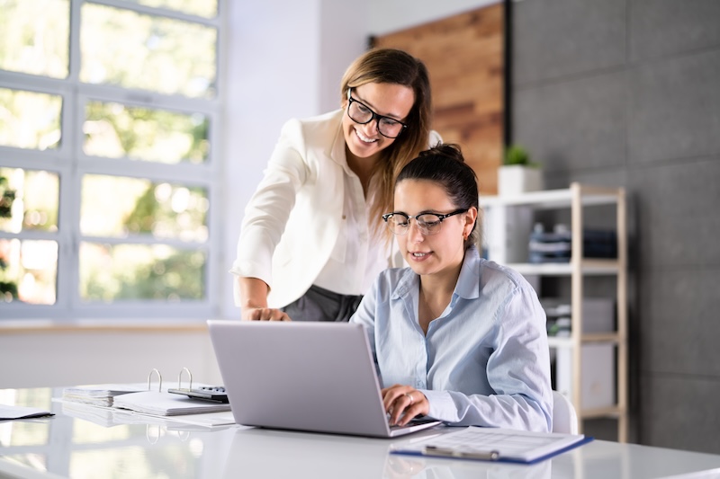 Clinic owner training a staff member on a laptop