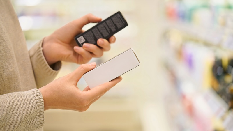 Consumer checking skincare product packaging and reading the ingredient label in a store.
