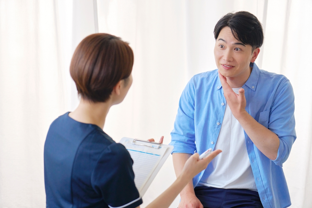 Male patient discussing facial aesthetic concerns with a practitioner during a consultation