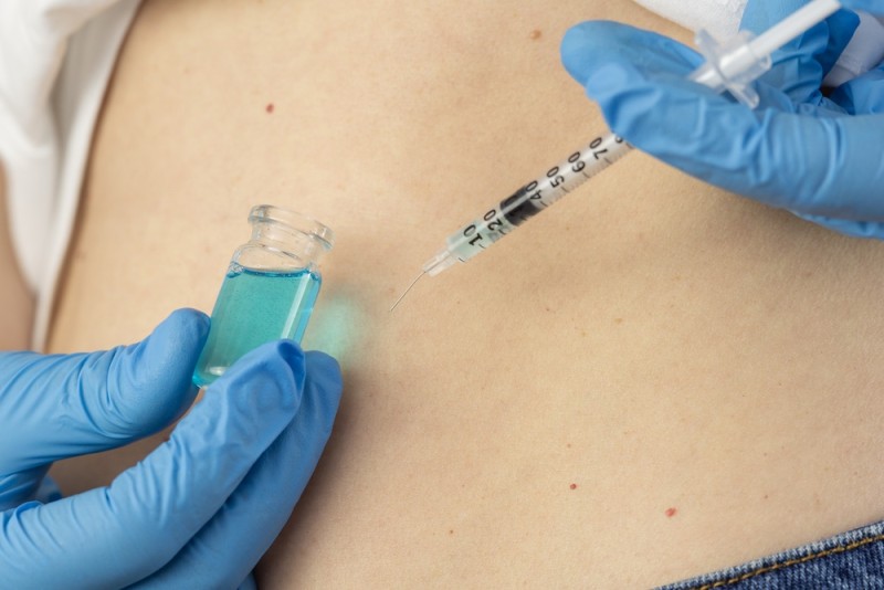Healthcare professional administering a copper peptide injection using a syringe and vial.