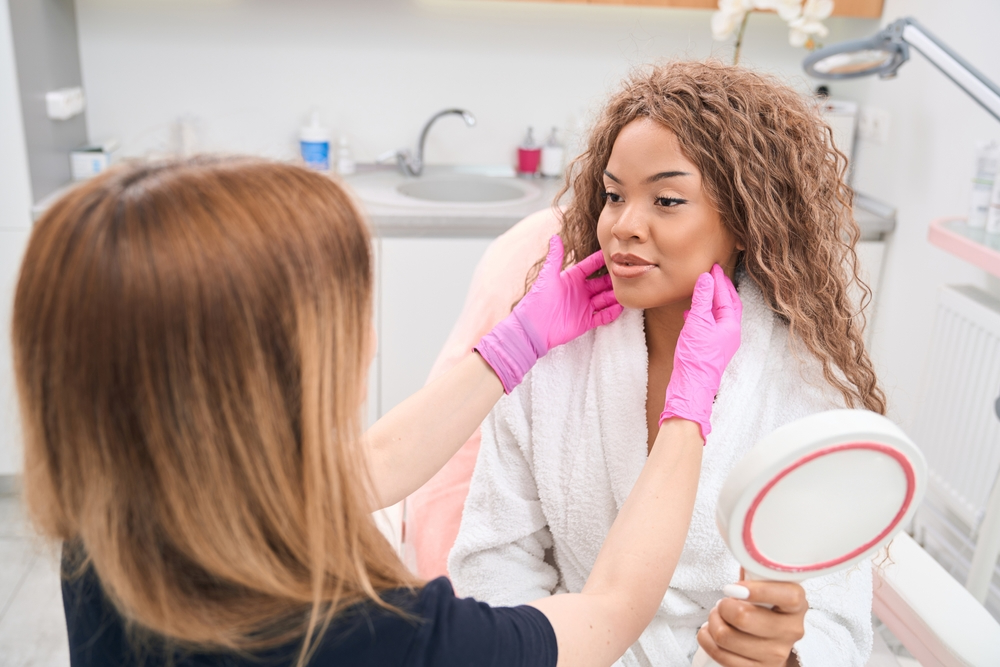 Aesthetic practitioner assessing a patient’s facial contours during a consultation