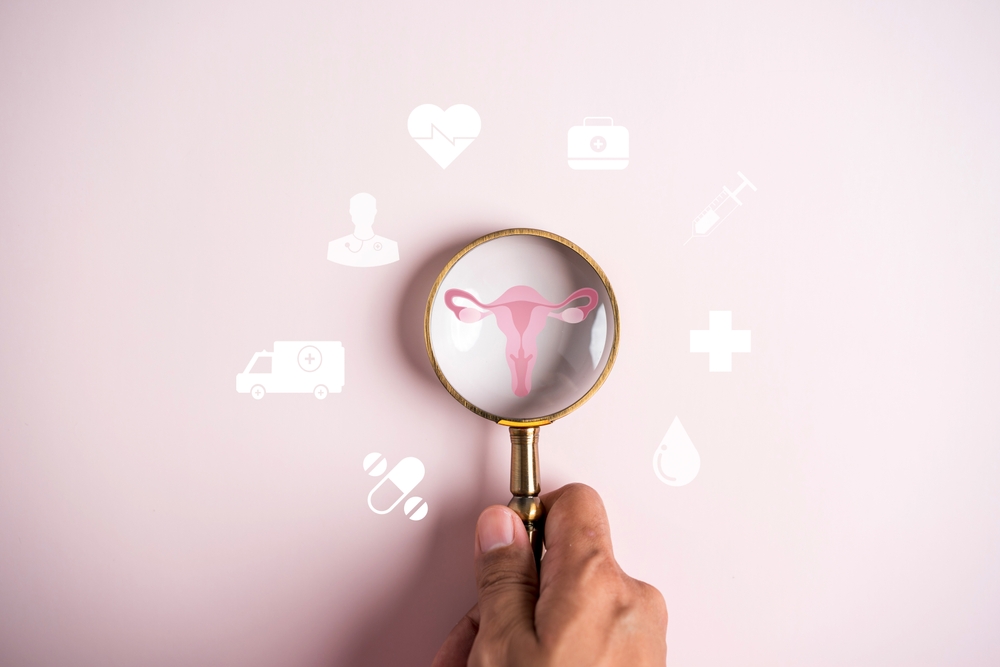 Magnifying glass showing a uterus and ovaries, surrounded by healthcare icons on a pink background.
