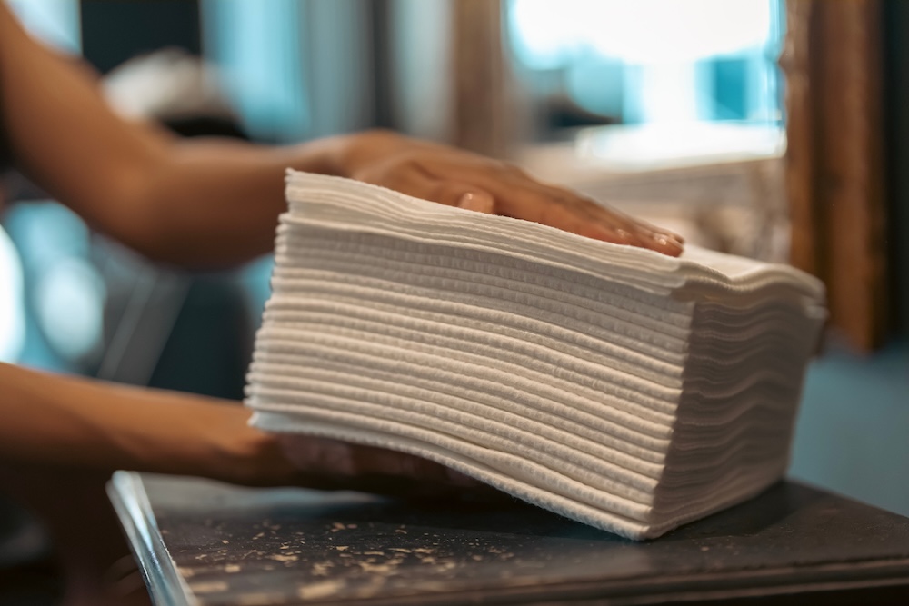 A hairdresser moving a stack of Scrummi towels in a salon